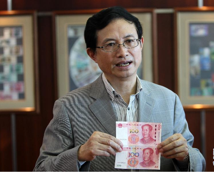 中国印钞造币总公司技术总监邵国伟在他的办公室展示新版百元钞票(上)与旧版的不同(10月30日摄)。