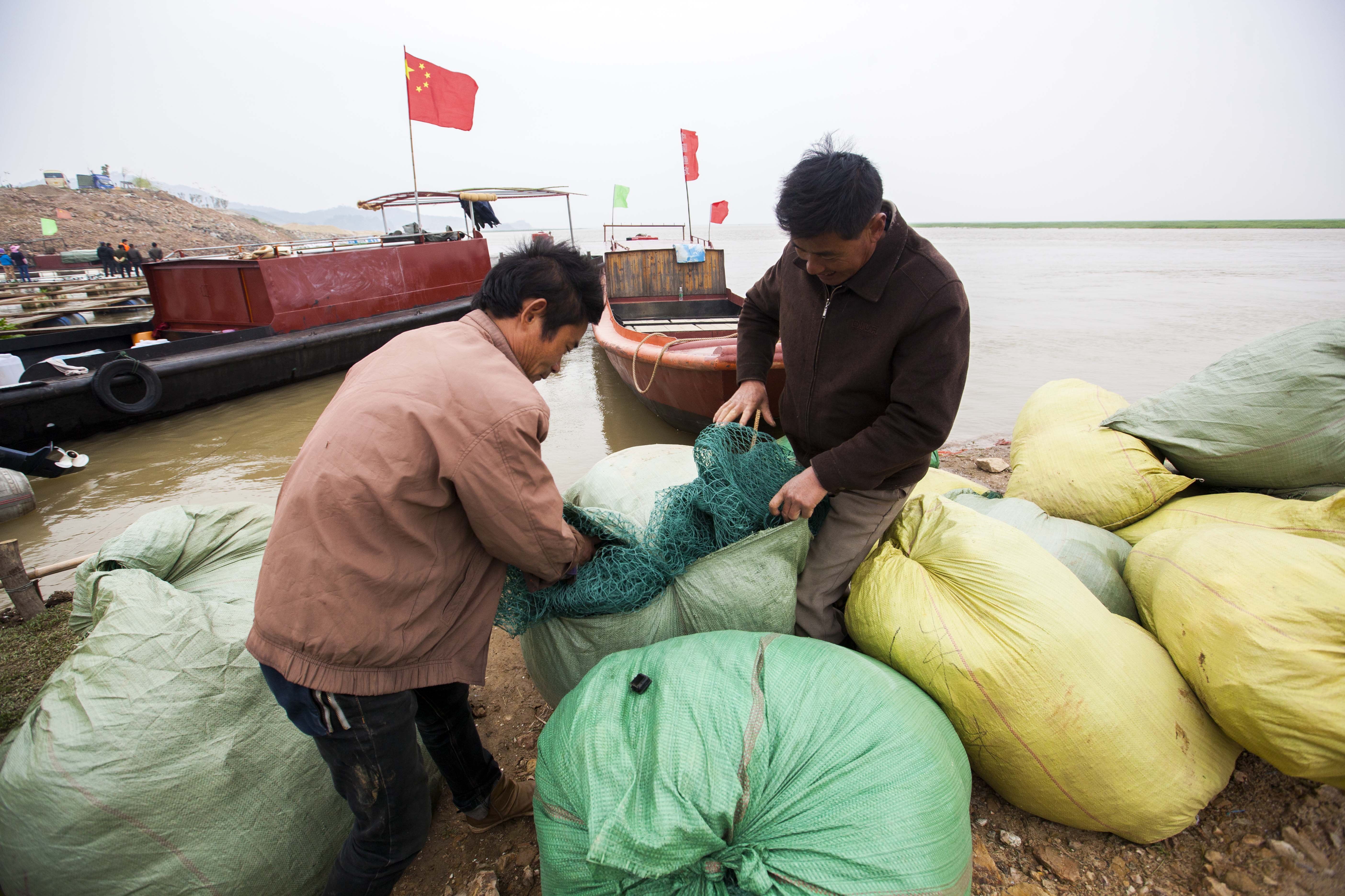 在江西鄱阳湖都昌城西码头，一名渔民在整理收拾渔网