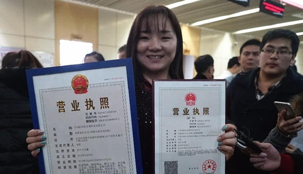江西国道贵金属贸易有限公司法定代表人李霞在展示她领到的南昌市首张“三证合一”营业执照和副本